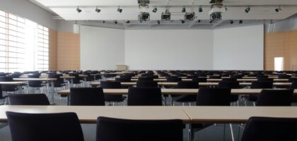 Spacious contemporary conference room with rows of tables and chairs, ready for meetings.